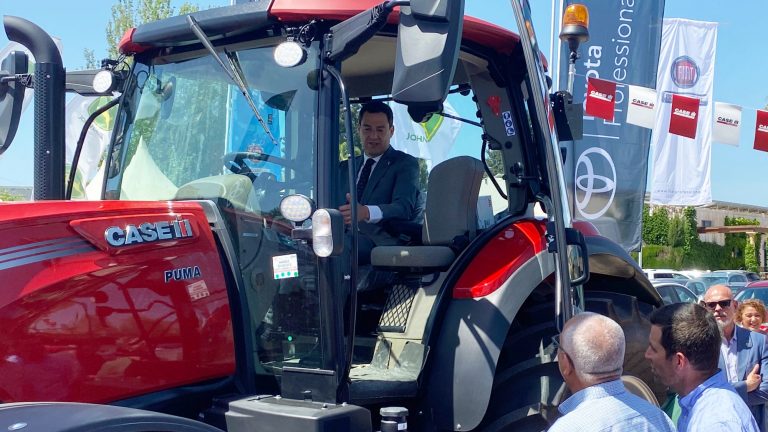 Juanma Moreno subido en un tractor expuesto en la Asamblea General de Asaja Málaga 2022