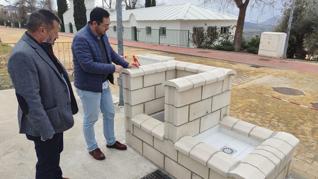 Los ediles Julián Morales y Pablo Garrido, junto a la toma de agua habilitada en el futuro aparcamiento de autocaravanas de Archidona (marzo 2025)